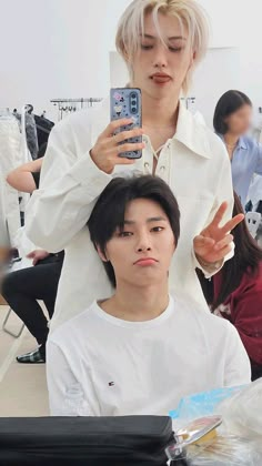 a man getting his hair cut by a woman in a white shirt and black pants