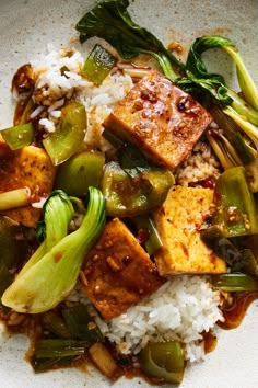 a white plate topped with tofu, rice and veggies next to broccoli