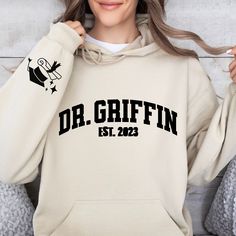 Looking for a unique and personal gift for a recent or soon-to-be PhD graduate? Look no further than this customizable PhD sweatshirt! Our sweatshirts are made from high-quality materials and come in a range of sizes to fit any body type. Plus, with the option to personalize the name on the sweatshirt, it's a one-of-a-kind gift that's sure to be treasured for years to come. To order, simply choose your preferred size and color, then enter the name you want to appear on the sweatshirt. We use onl Phd Shirt, Phd Humor, Med Student Gift, Phd Gifts, Future Doctor, Graduation Shirts, Sweatshirt Shirt, School Shirts, Black And Navy