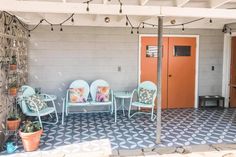 a patio with chairs and potted plants in front of a door on the wall