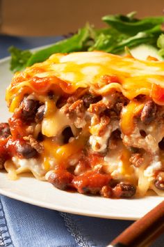 a white plate topped with lasagna next to a salad