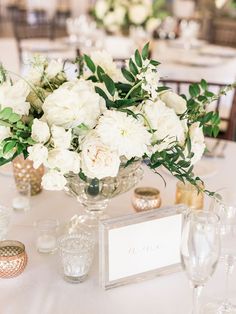 the centerpieces are arranged in glass vases with white flowers and greenery