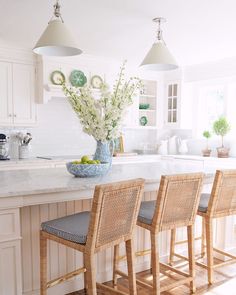 a kitchen island with four chairs and a bowl of fruit on the counter in front of it