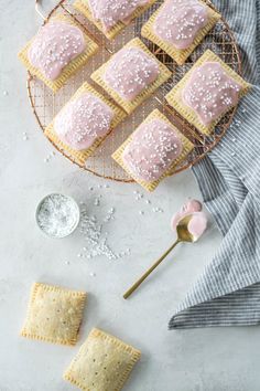 some crackers are sitting on a wire rack with pink icing and sprinkles