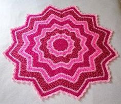 a pink crocheted doily is laying on a white tablecloth with an intricate design