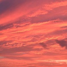 a person flying a kite in the sky at sunset or sunrise with pink and orange clouds