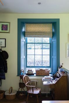 a room with a desk, chair and window that has blue trim on the windowsill