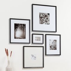 four black and white pictures hanging on the wall next to a vase with flowers in it