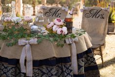 the table is set up with two chairs and some flowers on it, along with bottles of wine