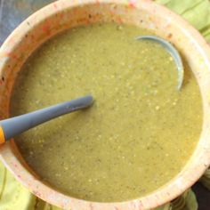 a bowl filled with green soup and a spoon