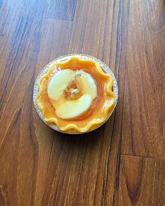 a pie sitting on top of a wooden table next to a plate with an apple in it