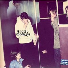 two young men standing next to each other in front of a mirror with the words arctic monkeys on it