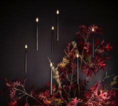 a vase filled with flowers and candles on top of a wooden table next to a wall