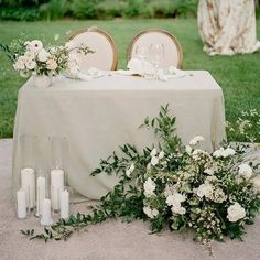 the table is set with white flowers and candles for an elegant wedding reception in the garden