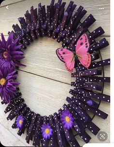 a wreath made out of purple sticks with butterflies on top and daisies in the middle