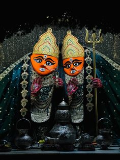 two statues of hindu deities with orange faces