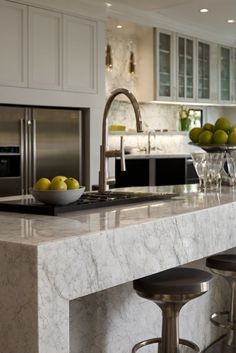 a kitchen with marble counter tops and stools in front of the sink, oven and refrigerator