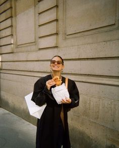 a woman is standing on the sidewalk eating food