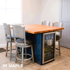 a kitchen island with two stools next to it and a wine cooler in the center