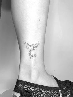 a woman's foot with a bird tattoo on the lower part of her leg