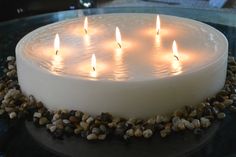 a white cake with lit candles on it sitting on top of a glass countertop