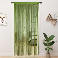 a living room with green curtains and a plant in front of the window on the wall