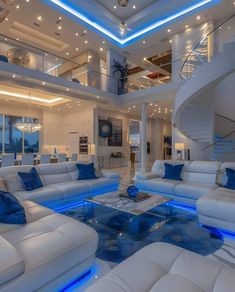 a living room filled with white couches and blue pillows next to a spiral staircase