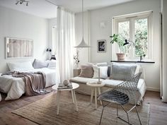 a living room filled with furniture and a white bed next to a window covered in curtains