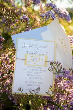 an open envelope with a heart on it sitting in the middle of some purple flowers