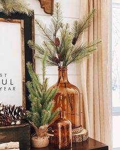 a vase with pine cones and greenery on a table