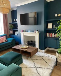 a living room with blue couches and a television mounted on the wall above a fireplace