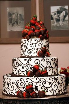 a three tiered cake with chocolate covered strawberries