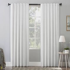 a living room with white curtains on the windowsill and a rug in front of it