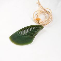 a large green leaf sitting on top of a white table next to a string and rope