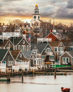 a small boat is in the water near some houses and a tower with a clock