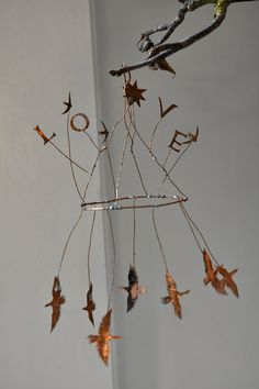 a wind chime with leaves hanging from it's sides and birds flying around