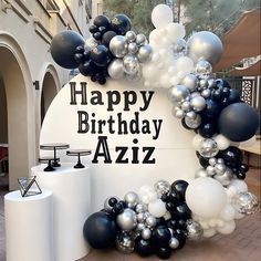 a happy birthday sign surrounded by black and white balloons