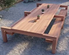 a wooden table with two potted plants on it in the middle of a gravel area