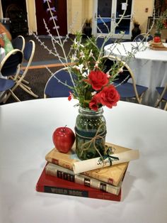 a vase filled with red roses sitting on top of books