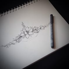 a pen is sitting on top of a paper with a flower tattoo design on it