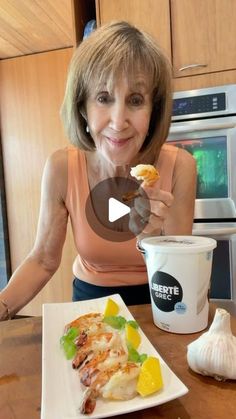 a woman sitting at a table with food in front of her and an ice cream cup