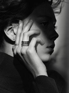 black and white photograph of a woman with her hand on her face, wearing two rings