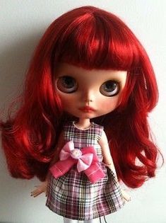 a close up of a doll with red hair wearing a dress and bow on it's head