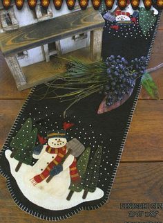 a table runner with a snowman on it and a small house in the background