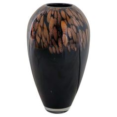 a black vase with brown and white designs on the outside, sitting in front of a white background