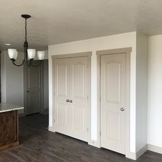 an empty room with three doors and a light hanging from the ceiling in front of it