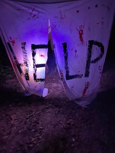 two tents with the word help painted on them are lit up in purple light at night