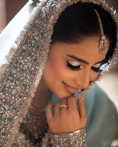 a woman in a bridal gown is smiling and looking at her ring on her finger