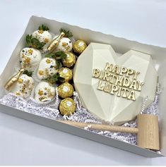 a birthday cake in a box with chocolates and strawberries on the table next to it