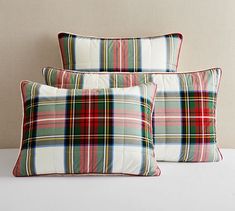 three plaid pillows sitting on top of a bed